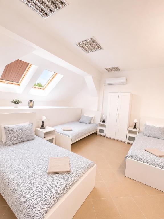 two beds in a white room with skylights at Konvoj szálló in Budapest