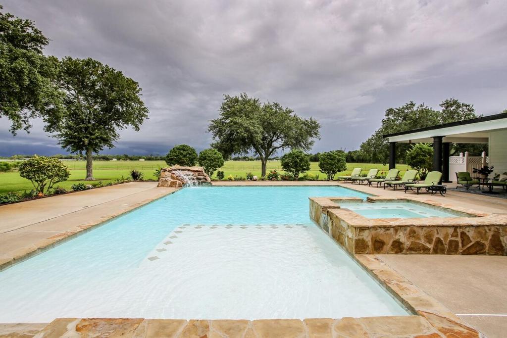 a large swimming pool with a stone wall around it at Private Luxury Pool House Retreat in Lake Charles