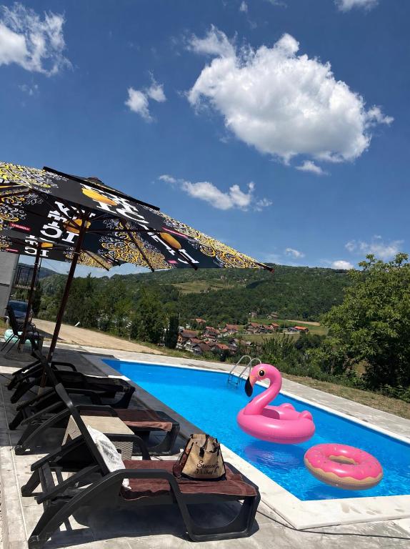 a swimming pool with two flamingos and an umbrella at Vikendica Dajana in Banja Luka