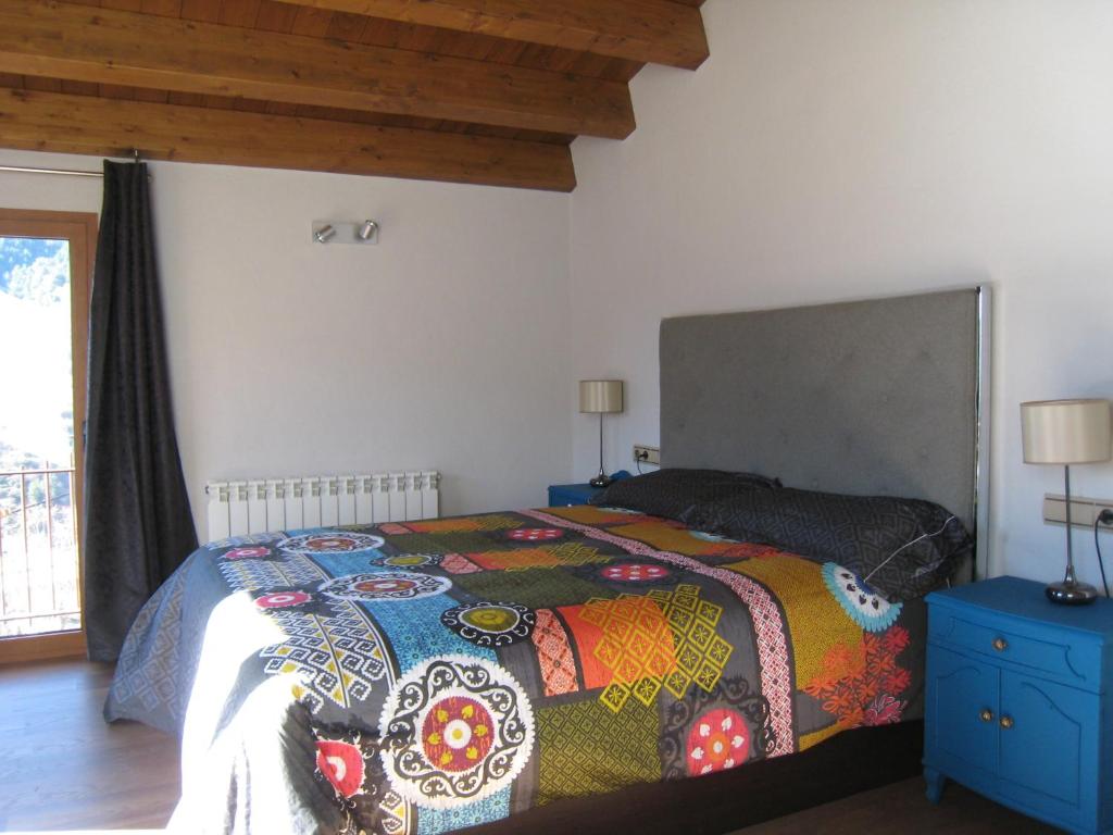 a bedroom with a bed with a colorful blanket at Ca l'Escolà in Aransá