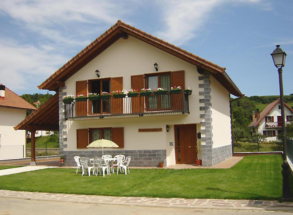 ein Haus mit einem Balkon mit Tischen und Stühlen in der Unterkunft Casa Rural Irugoienea in Espinal-Auzperri