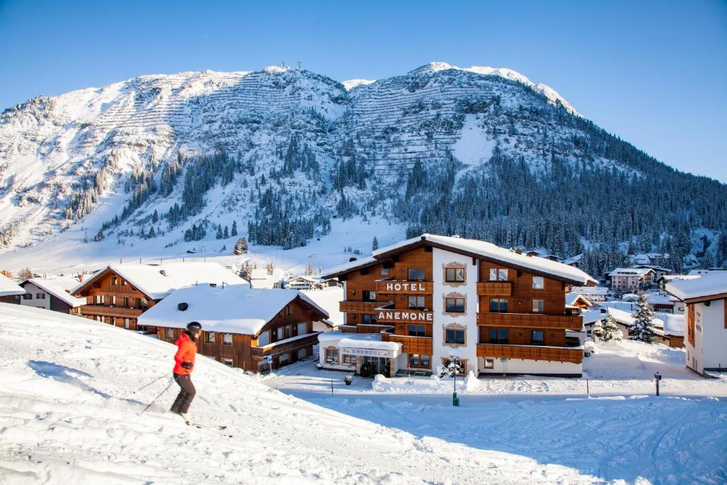 een persoon op ski's in de sneeuw voor een berg bij Hotel Anemone in Lech am Arlberg