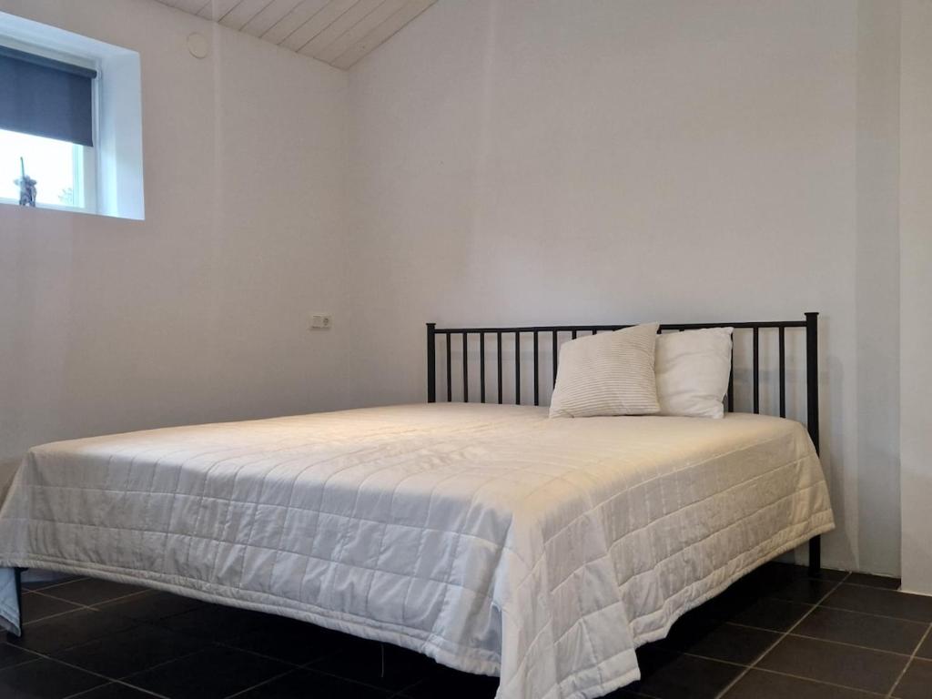 a bedroom with a bed with a white blanket and a window at Wonderfully unique accommodation in Bålsta
