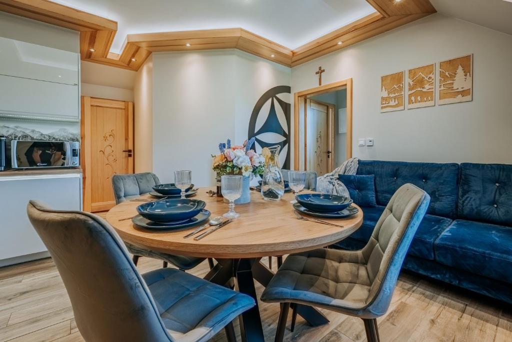 a dining room with a table and a blue couch at Apartament Między Górami in Kacwin