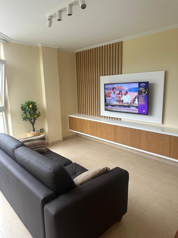 a living room with a black couch and a flat screen tv at Pilgrims House II in Lourenzá