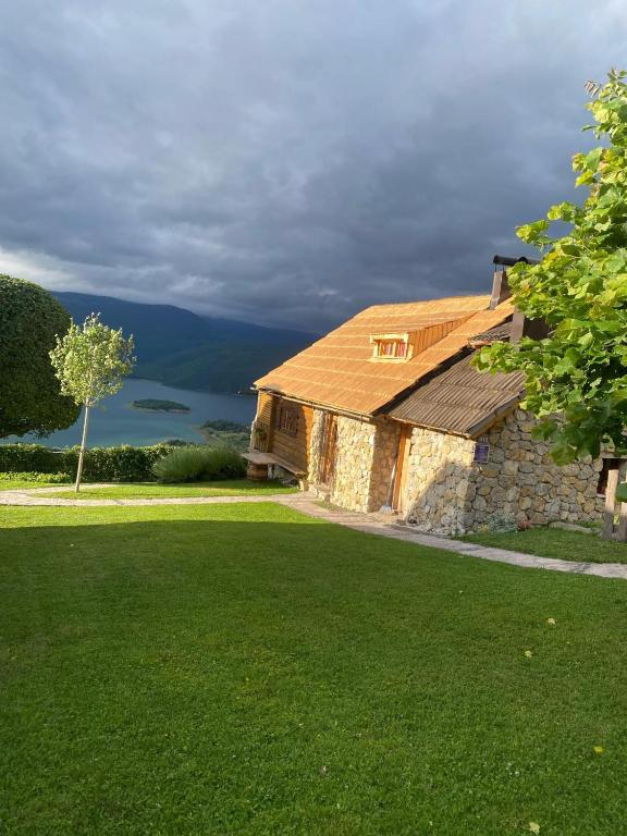 a stone house with a green lawn in front at Kuća za odmor Vidikovac in Rumboci