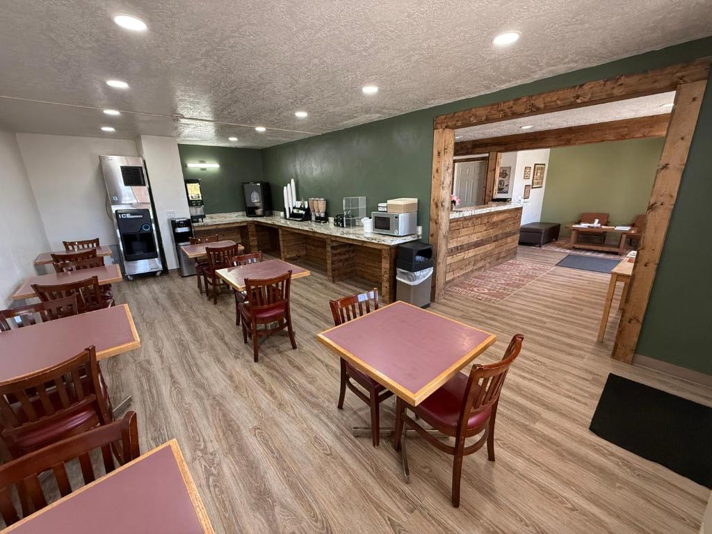 a dining room with tables and chairs and a kitchen at Four Corners Inn in Blanding