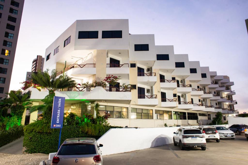 a white building with cars parked in a parking lot at Petrolina Palace Hotel in Petrolina