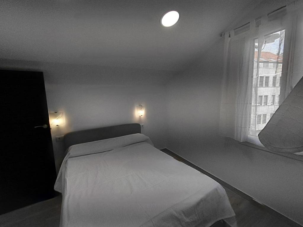 a bedroom with a white bed and a window at Rua de Galicia 2 in Ribeira