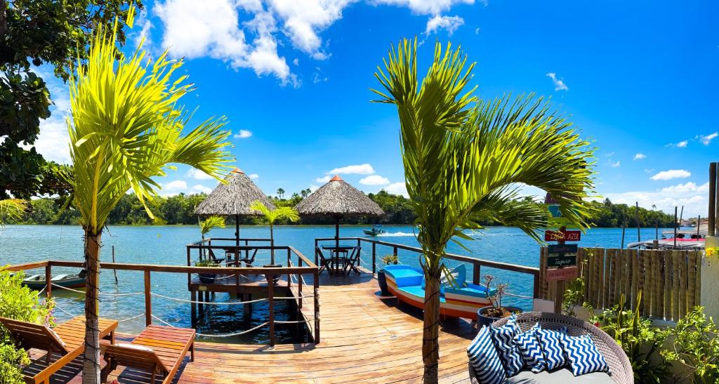 a dock with chairs and a boat on the water at Pousada Do Porto in Barreirinhas