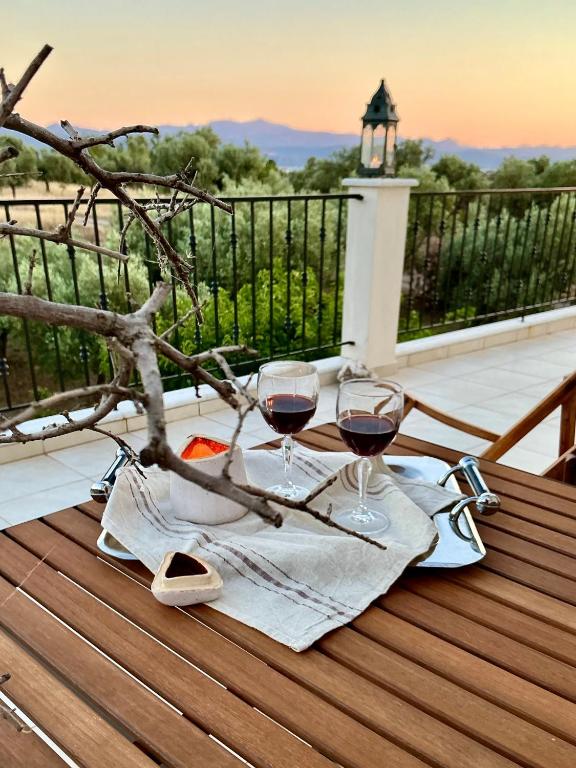 a table with two glasses of wine on a deck at Horizon House, with Olive Grove and a small Vineyard in Amarynthos