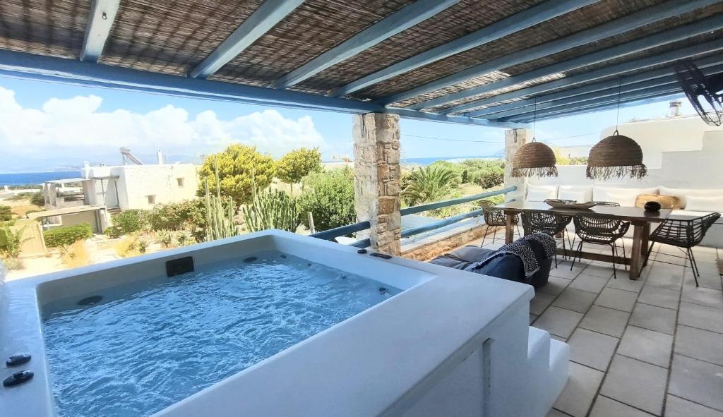 a large bath tub on a patio with a table at Island Magic - Seaview Villa with Jacuzzi Pool in Ambelas