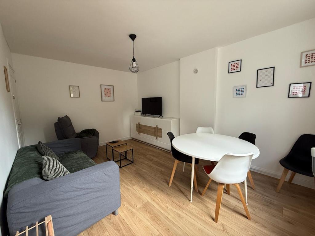 a living room with a couch and a table at Charmante petite maison - 2 chambres in Homécourt