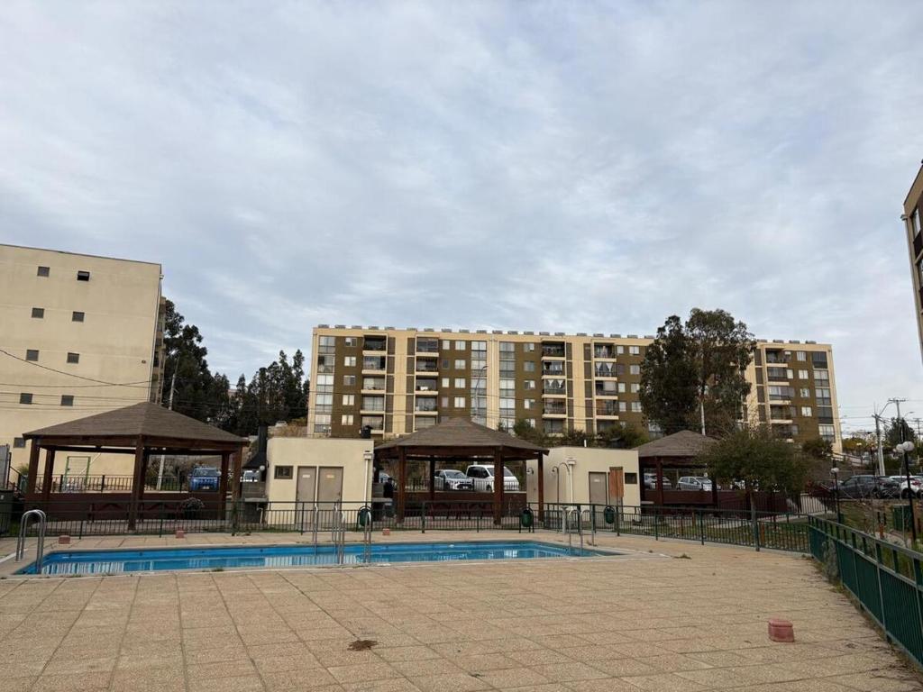 a swimming pool with a building in the background at Comodo departamento 2 dormitorios con piscina in Quilpué