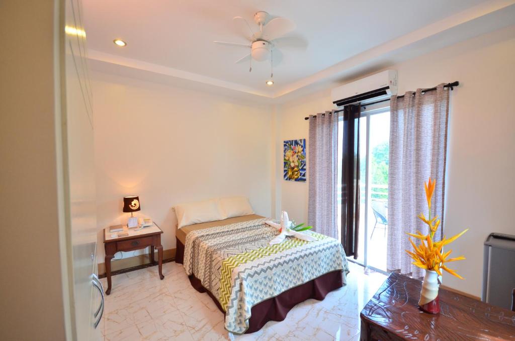 - une chambre avec un lit, une table et une fenêtre dans l'établissement Villa de Sierra Vista Bay and Mountain View Inn, à Puerto Princesa