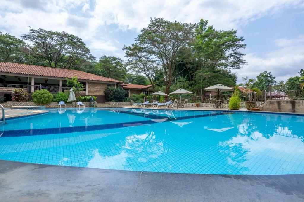 a large blue swimming pool with chairs and umbrellas at Sagana Getaway Resort in Maranjua