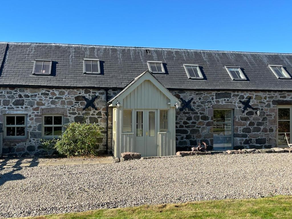 a stone house with a dog sitting in front of it at Semeil Farm Holiday Lets in Strathdon