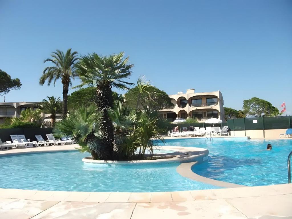 a pool at a resort with palm trees in it at Studio Riviera de Bahia in Villeneuve-Loubet