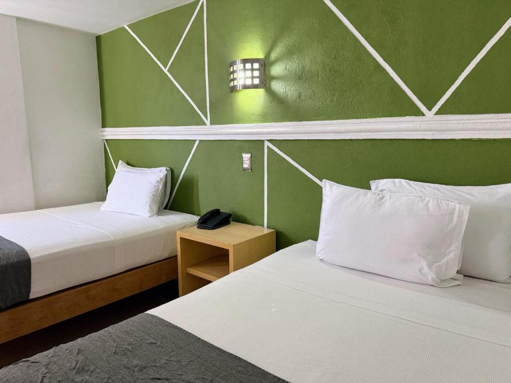zwei Betten in einem Zimmer mit grünen Wänden in der Unterkunft Hotel Nueva Zelanda in León