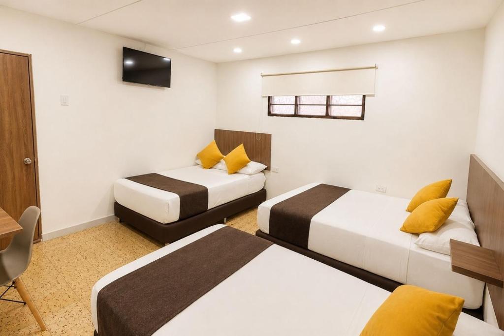 a hotel room with two beds and a television at Ayenda Hotel Helenas in Ríohacha