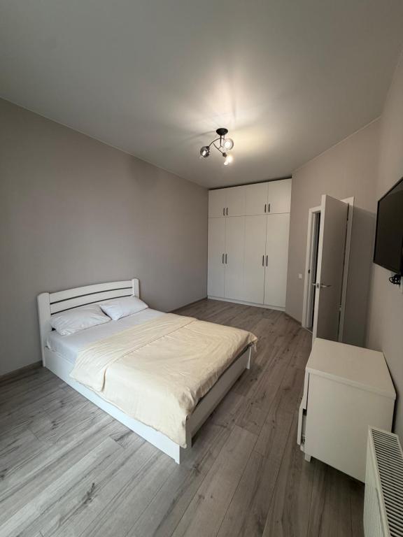 a white bedroom with a large bed and wooden floors at Яровиця 167 in Lutsk