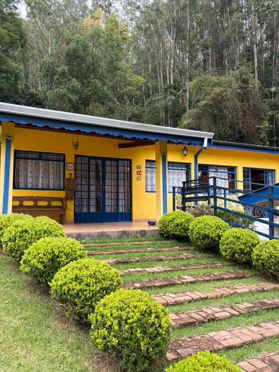 a yellow house with bushes in front of it at Pousada A Casa da Fazenda in Santo Antônio do Pinhal