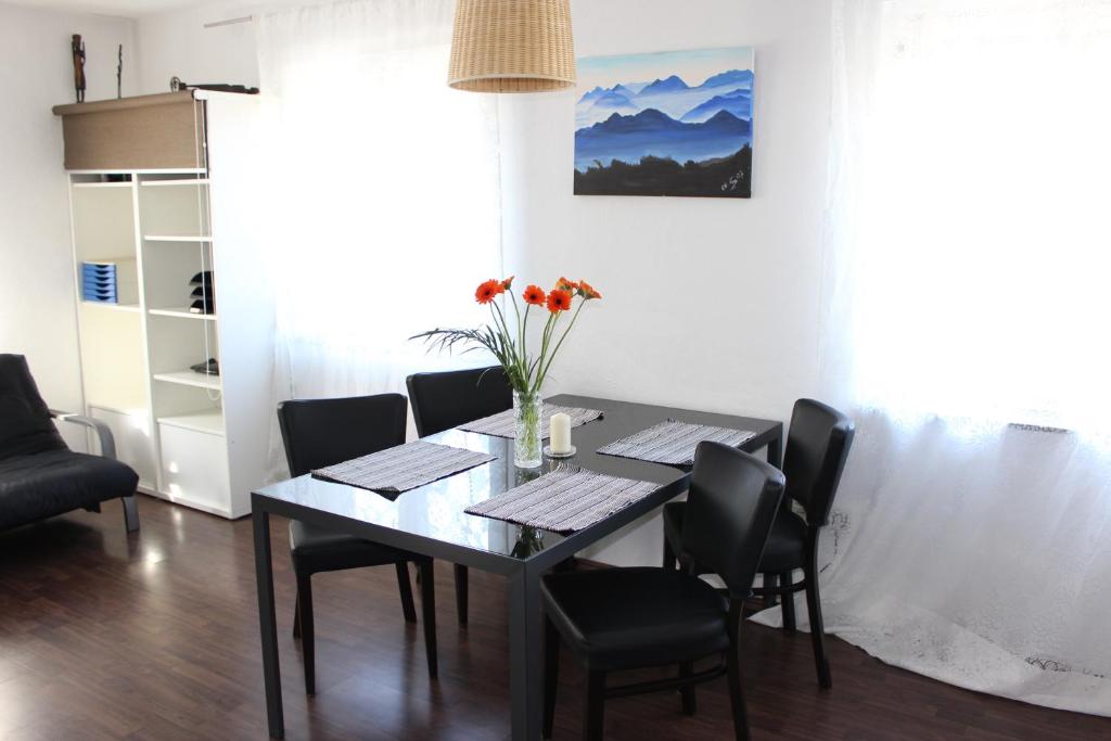 a dining room table with black chairs and a vase of flowers at Ferienwohnung Fischach in Fischach