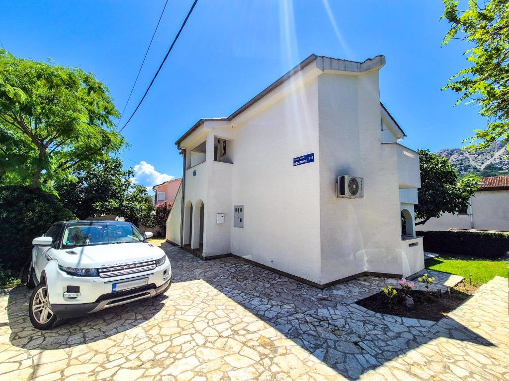 a car parked in front of a white building at Apartments Benkovic in Baška