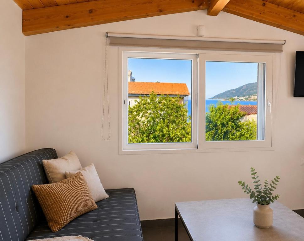a living room with a couch and two windows at Ocean Breeze Luxury Loft in Psathopyrgos