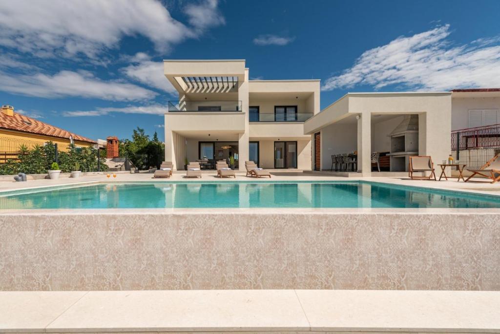 a villa with a swimming pool in front of a house at Villa Infinity in Rtina