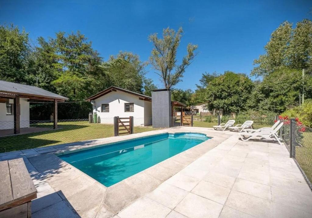 a swimming pool with chairs and a house at Cabañas Siddharta in Los Reartes