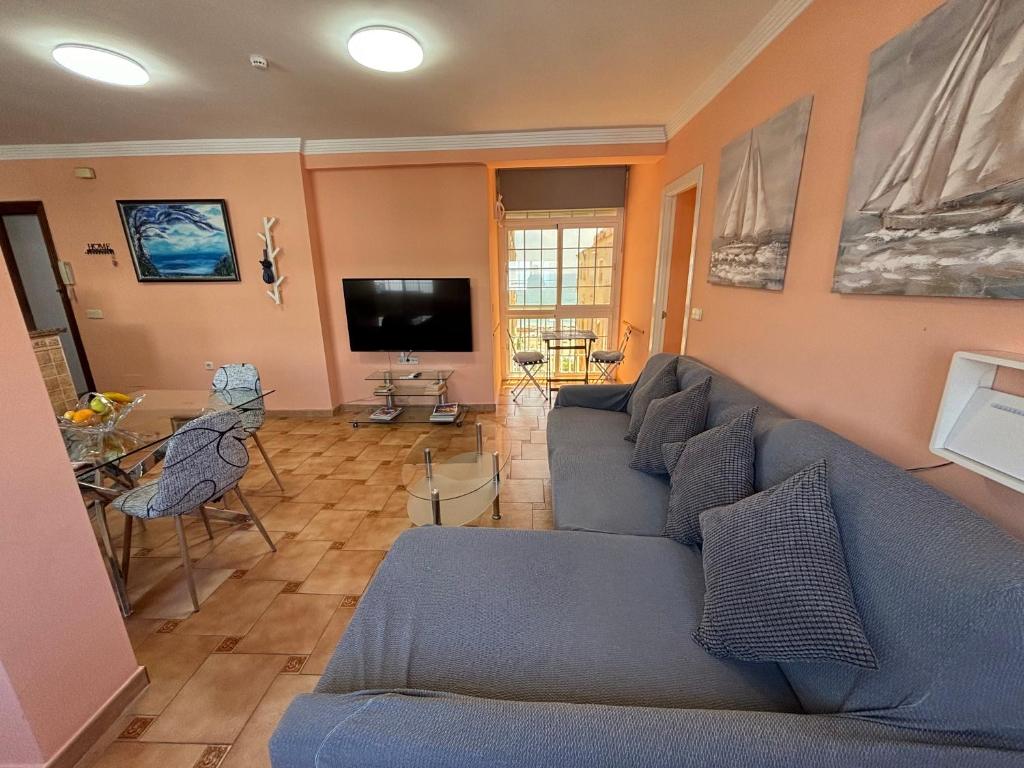 a living room with a blue couch and a tv at Las Delicias de Estepona in Estepona