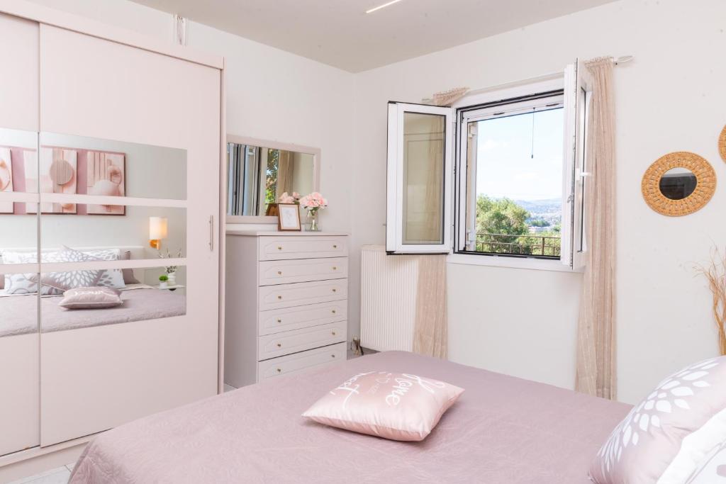a white bedroom with a bed and a window at La Casa Seni Near Athens Airport in Papangeláki