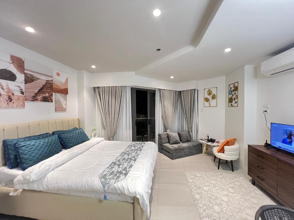 a bedroom with a large bed and a television at Tambuli Seaside Living Pad seaview in Maribago