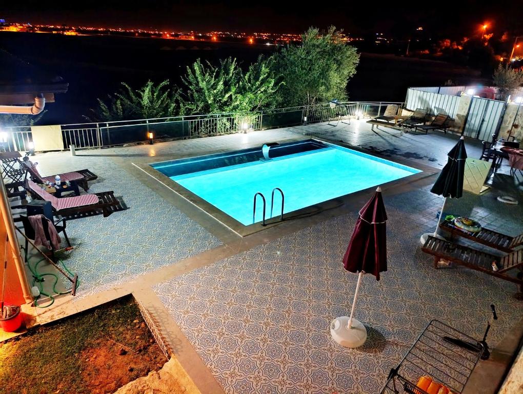 a swimming pool with a table and an umbrella at Aze's Garden suites - Kalkan, Kaş in Kaş