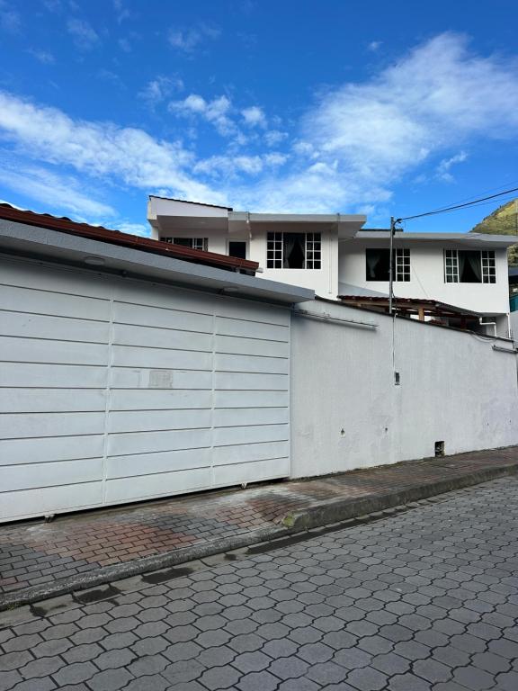 a white building with two garage doors next to a street at Amazing Home - Habitación Triple in Baños