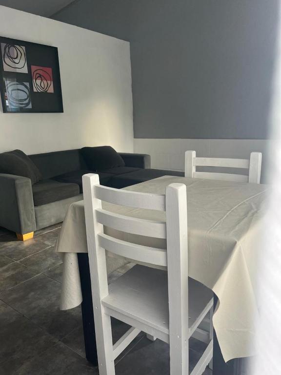 a white chair in a living room with a couch at Tu rincón, lugar de descanso in Chascomús
