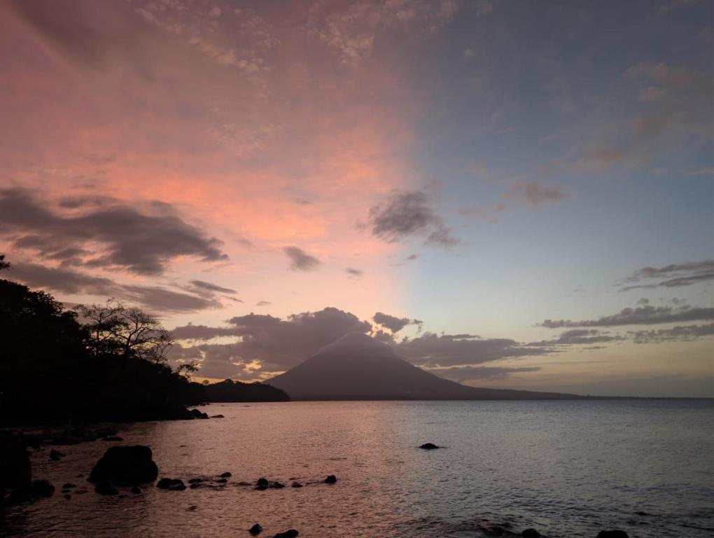 a sunset over a body of water with a mountain at Rocks Beach in Balgue