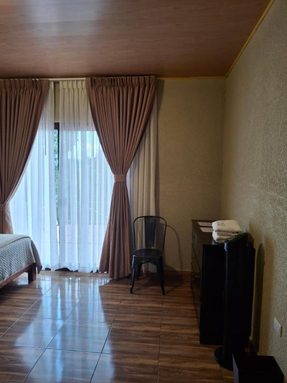 a bedroom with a bed and a chair next to a window at Finca La Concepción in Marcala