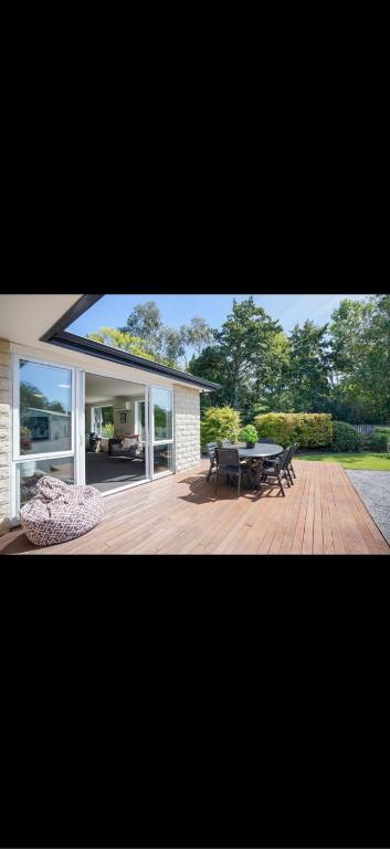 a house with a deck with a table and chairs at Otatara Bush Haven in Otatara