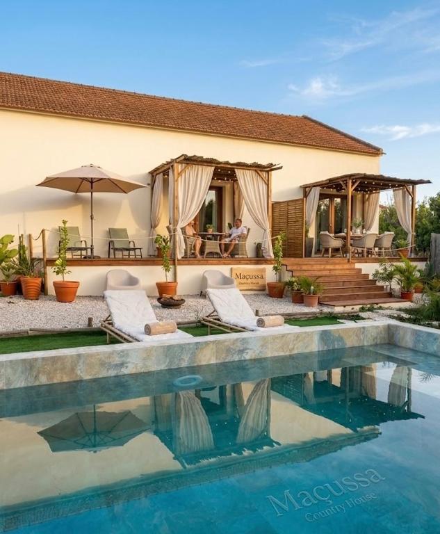 a house with a swimming pool in front of a house at Maçussa Country House in Massuça