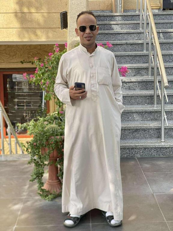 a man standing in front of some stairs holding a cell phone at Akhnaton pyramids inn in Cairo