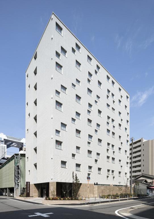 a large white building on the side of a street at S.Training Center Hotel Osaka in Osaka