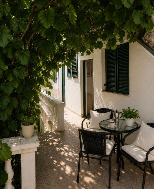 a patio with a table and chairs under a tree at Studios Annie in Bijela