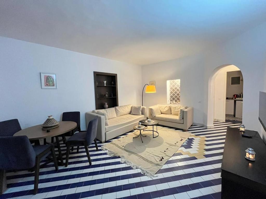 a living room with a couch and a table and chairs at Cosy 1BD Pool, Beach, Large Terrace in Hammam Sousse