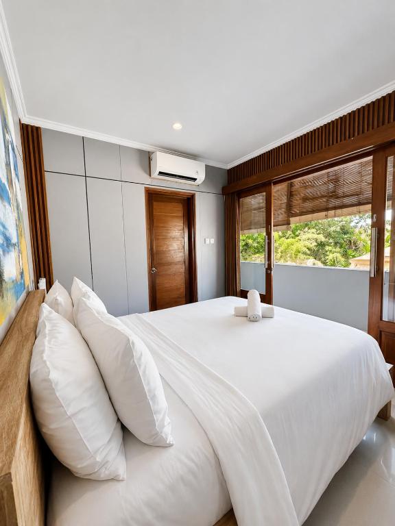 a bedroom with a large white bed with white pillows at Dana Homestay in Canggu