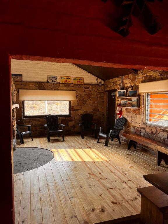 a living room with chairs and a piano in a cabin at Refugio Pehuenche in Los Molles