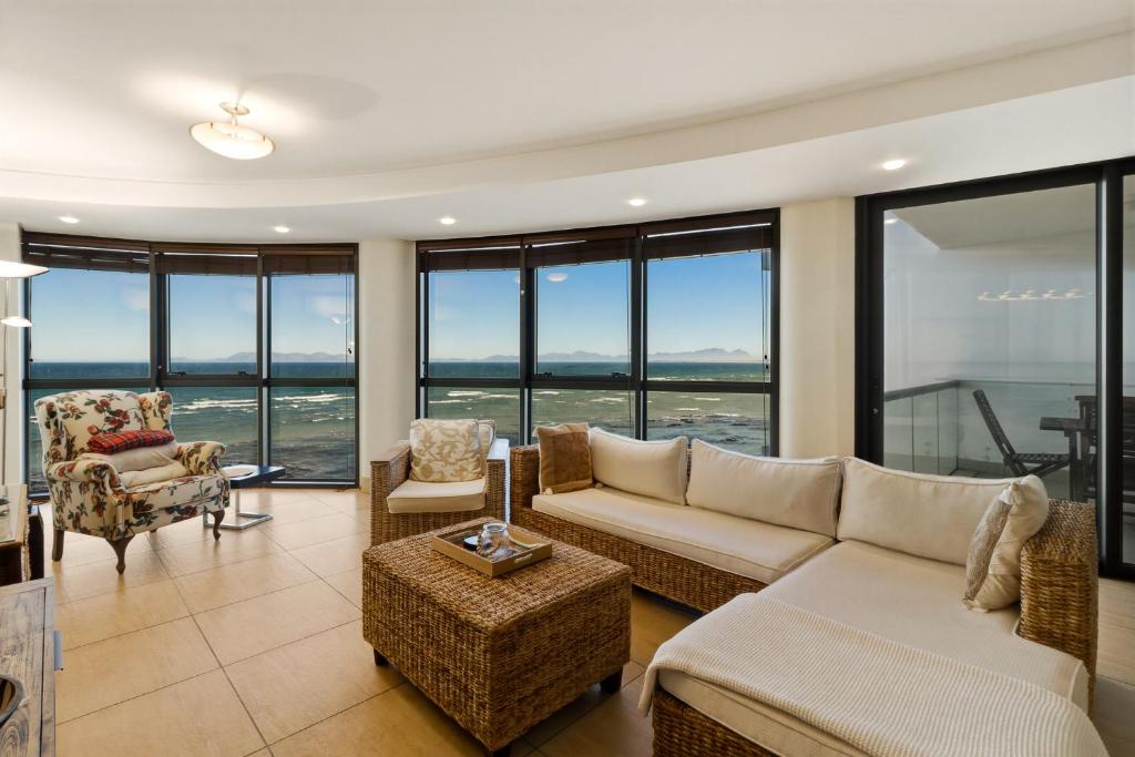 a living room with a couch and chairs and windows at Luxury Ocean View 1203 with Workspace, AC & Beachfront Location in Cape Town