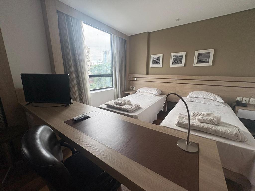 a room with two beds and a desk with a mirror at Intercity - Apartmento 412 in Manaus