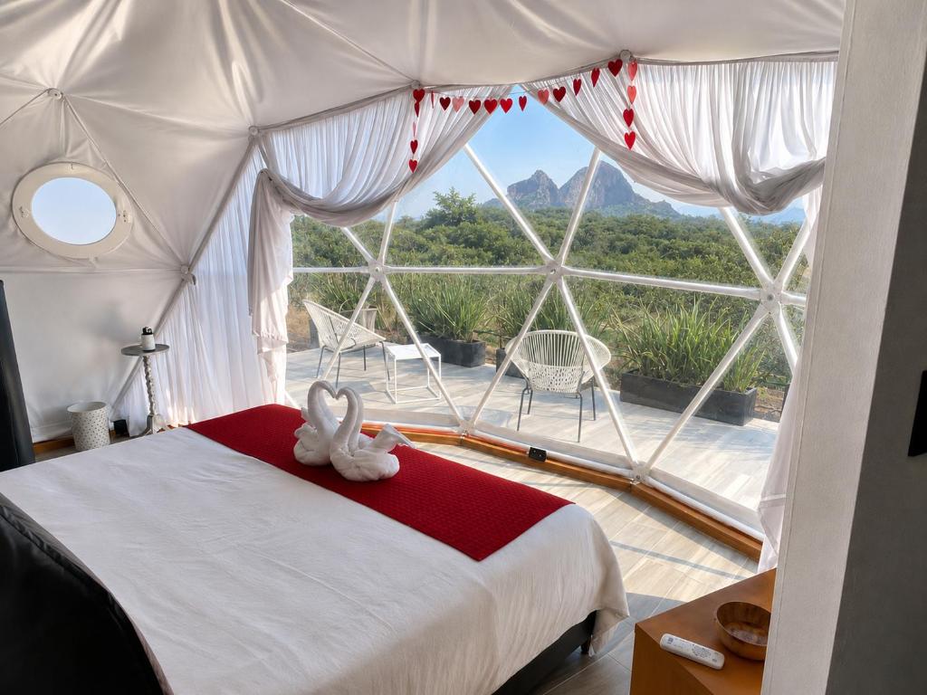 a bedroom with a bed and a large window at Romantic Dome & French Cuisine in Jantetelco